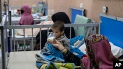 A woman gives milk to her 2-year-old son as he undergoes treatment in the malnutrition ward of a hospital in Kabul. 