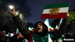A man gestures while displaying the Lion and Sun emblem -- used by Iran for its national flag before the 1979 Islamic Revolution-- as demonstrators gather outside the Iranian Embassy in London on January 11 during a rally in support of nationwide protests in Iran.