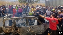 Civil defense workers and citizens inspect the remains of a car that was hit by an Israeli strike in the southern port city of Sidon, Lebanon, on August 26.