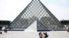 FRANCE - FILE PHOTO: Tourists stand in front of the Louvre Pyramid designed by Chinese-born U.S. Architect Ieoh Ming Pei in Paris, France, September 13, 2016