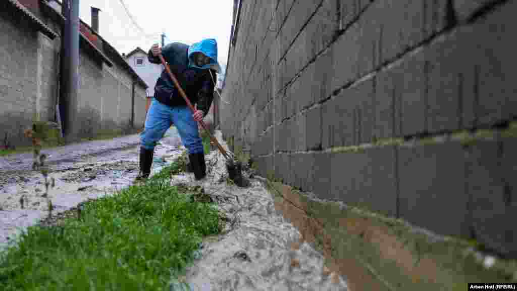 Jedan građanin pokušava očistiti poplavljenu ulicu u Mališevu.