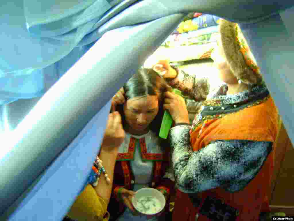 The groom&#39;s sisters treat the bride&#39;s hair with a mixture of milk and pine needles and arrange her hair into two braids, the style for married women.