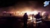 People stand in front of flames rising after an attack on an area known to have numerous Syrian army military bases, in Kisweh, south of Damascus, May 9, 2018