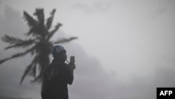 مردی در حال استفاده از تلفن همراه در جریان طوفان قدرتمند