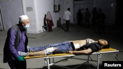 An Afghan man wheels an injured man in a hospital after a suicide bombing in Kabul on October 24.