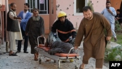 A body is removed from the scene of a suicide attack that targeted the Afghan state television building in Jalalabad in May.