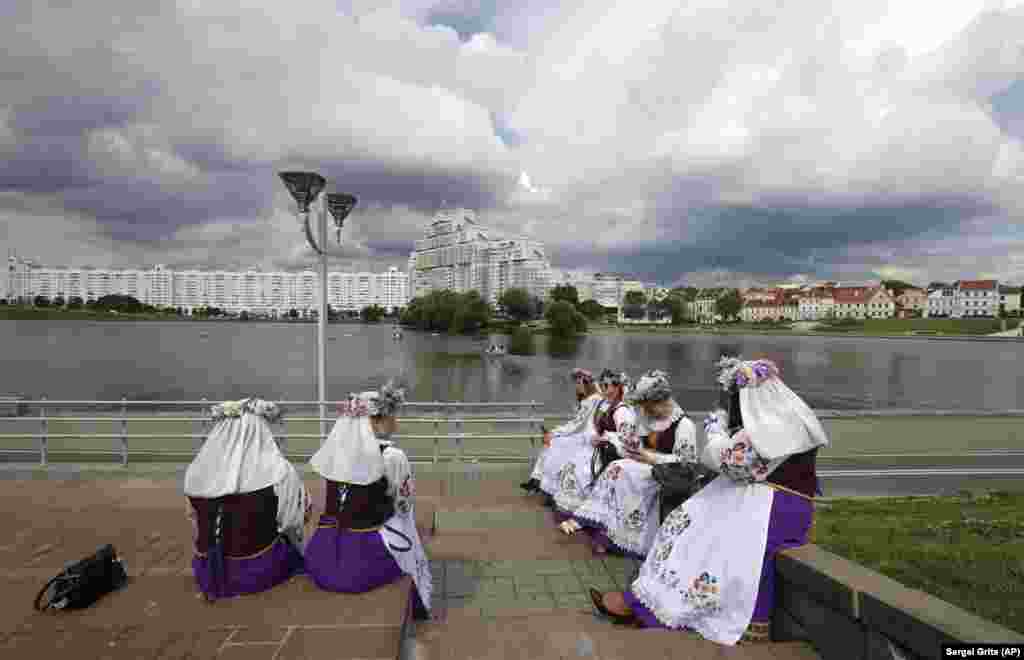 Women wearing Belarusian national dress sit on the embankment as they wait to take part in a concert on the eve of Independence Day in Minsk on July 2. (AP/Sergei Grits)