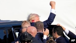  Малко след стрелбата Тръмп протяга пестник нагоре. 