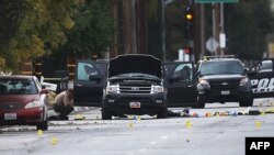 Law-enforcement officials investigate the Ford SUV vehicle that was the scene where suspects of the shooting at the Inland Regional Center were killed on December 3 in San Bernardino, California. 