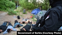 Migranti sa rukama na glavama, nakon što je srpska policija otkrila ilegalni kamp u opštini Novi Kneževac na severu Srbije. Ovu fotografiju objavila je srpska policija, 4. jula 2021. 