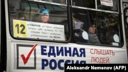 Люди едут в автобусе, украшенном предвыборным плакатом партии «Единая Россия» в сибирском городе Томск. 7 сентября 2020 года.