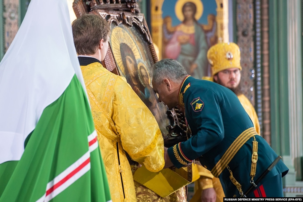 Defense Minister Shoigu (center) bows in front of a religious icon.