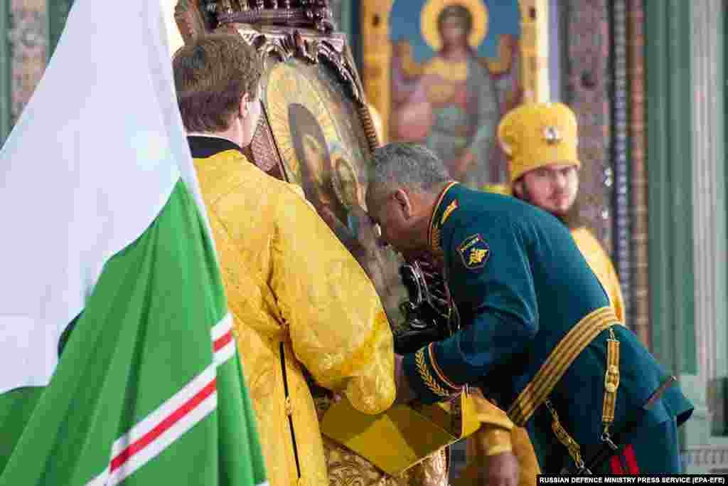 Defense Minister Shoigu (center) bows in front of a religious icon.