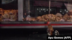Петел стои до излог на кој е изложено пилешко месо во продавница за живина во фавелата Мандела во Рио де Жанеиро, Бразил, архивска фотографија 
