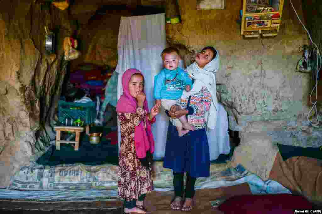 Afghan ethnic Hazara children stand in their cave on a cliff pockmarked by caves, where people still live as they did centuries ago in Bamiyan.