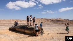 People stand on top of the remains of an Iranian missile in the Negev desert near Arad, Israel on October 2.