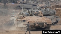 Israeli armored personnel carriers and tanks maneuver in a staging area in northern Israel near the Israel-Lebanon border on October 1.