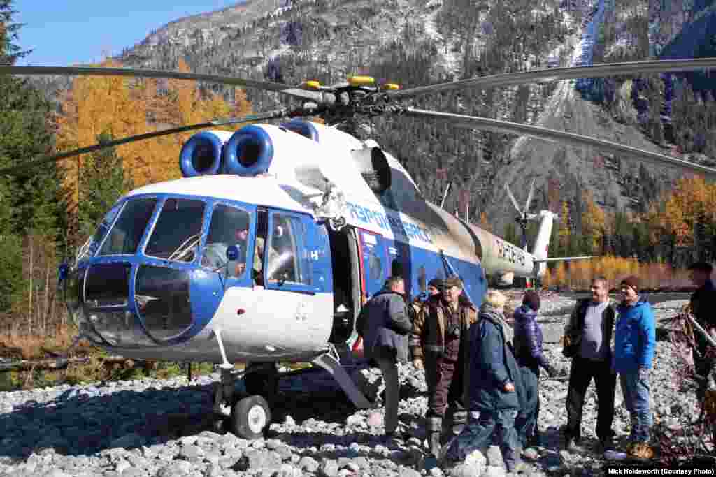 Visitors, including filmmakers planning a documentary, arrive by helicopter on a rocky bank of the Abakan River near the home of Agafia Lykova.