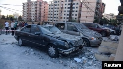 People stand at the site hit by an Israeli strike in the northern Lebanese city of Tripoli