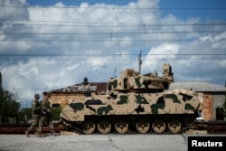 Военнослужащие США проходят мимо боевой машины пехоты Bradley по прибытии на совместные американо-грузинские учения Noble Partner 2016 в Вазиани