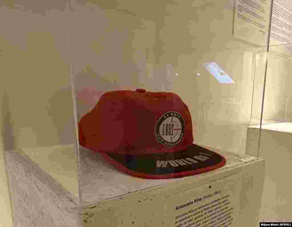 "Nisam sanjala da ću se baviti ratnim zločinima, skupljati tuđe suze i hodati po zgarištima", piše novinarka Antonela Riha, rođena u Kotoru.Sigurna kuća za vreme „tragičnih devedesetih“ od 1996. bio joj je Radio B92. "Odmah sam znala da mi je tu mesto". Na izložbi je istaknut kačket upravo ovog medija.