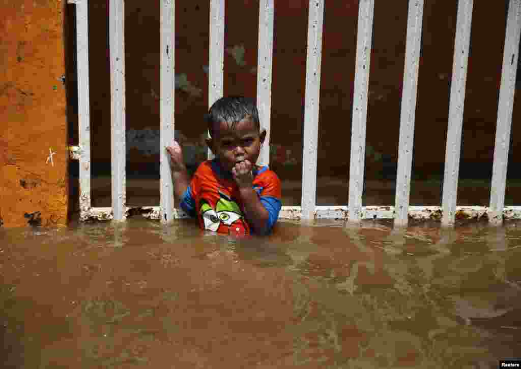 A child holds on to a fence at his house during a flood at the Kampung Melayu residential area in Jakarta on December 23. (Reuters/Beawiharta)