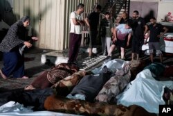 Palestinienii își plâng rudele ucise în atacul împotriva școlii ONU din tabăra de refugiați Nuseirat.