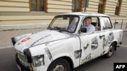 An East German Trabant decorated with reproductions of newspaper stories of the 1989 Pan-European Picnic arrives for the 20th anniversary of the gathering in Sopron.