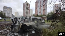 In a handout photograph released by Ukrainian emergency services on September 24 a Ukrainian rescuer works next to burned-out cars at the site of an air attack in Kyiv.