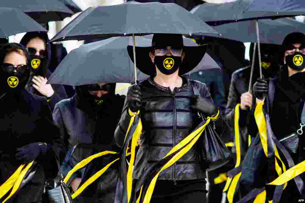 Women wearing black clothing and face masks with the radioactivity sign march under umbrellas in Minsk on April 26 to commemorate victims of the Chernobyl nuclear disaster on the 35th anniversary of the tragedy. (AFP)