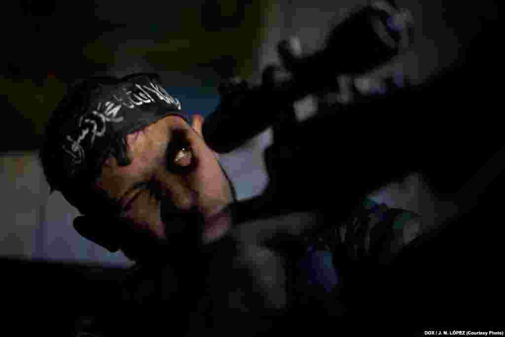 Abu Sufien, 30, aims his weapon while looking for a target inside a living room of a destroyed building in the Izaa district of the northern Syrian city of Aleppo on December 30, 2012.