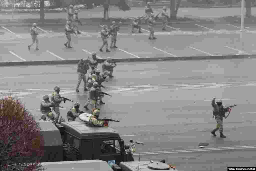 Militari neidentificați trag cu armele în centrul orașului Almatî, pe 6 ianuarie. În înregistrarea video a acestei scene, bărbatul din dreapta pare să facă semn să se oprească din tras după o rafală susținută de focuri de armă din partea formațiunii.