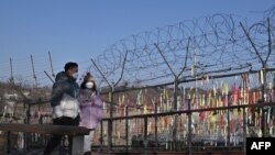 Posjetioci prolaze pored vojne ograde ukrašene vrpcama sa željom za mir i ponovno ujedinjenje Korejskog poluostrva u parku mira Imjingak u blizini "demilitarizovane zone" koja dijeli dvije Koreje u Pajuu, 1. januar 2022.