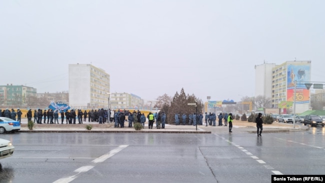 Биліктен сұйытылған газ бағасын түсіруді талап етіп тұрған адамдар мен оларды бақылап жүрген полиция. Ынтымақ алаңы, Ақтау, Маңғыстау облысы, 3 қаңтар 2022 ж.