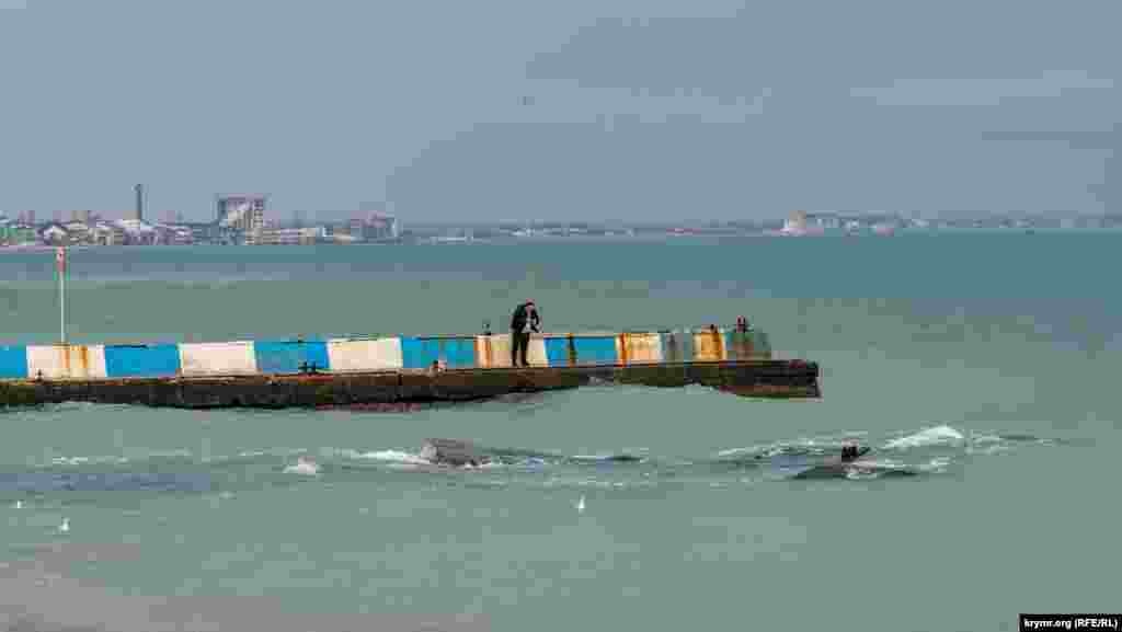 Мужчина с буна фотографирует на смартфон зимнее море