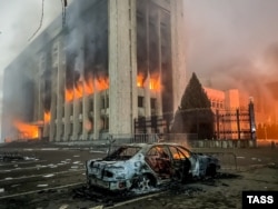 Январские события в Казахстане. Сгоревший автомобиль возле горящего здания акимата Алматы. Участники протеста против роста цен на топливо ворвались в здание акимата и подожгли его. 5 января 2022 года