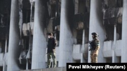 Вооруженная охрана у сожженного здания акимата Алматы