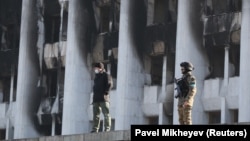 Сотрудники сил безопасности у здания акимата в Алматы, горевшего после начала протестов, поводом для которых послужило повышение цен на газ.