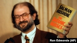 Salman Rushdie arătând un exemplar din controversatului său roman „Versetele satanice” la o conferință de presă, Arlignton, comitatul Virginia, Statele Unite, 1992.