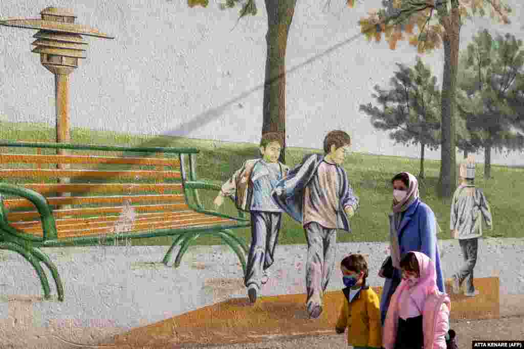 A woman and children walk past a mural at a park in the Iranian capital, Tehran.