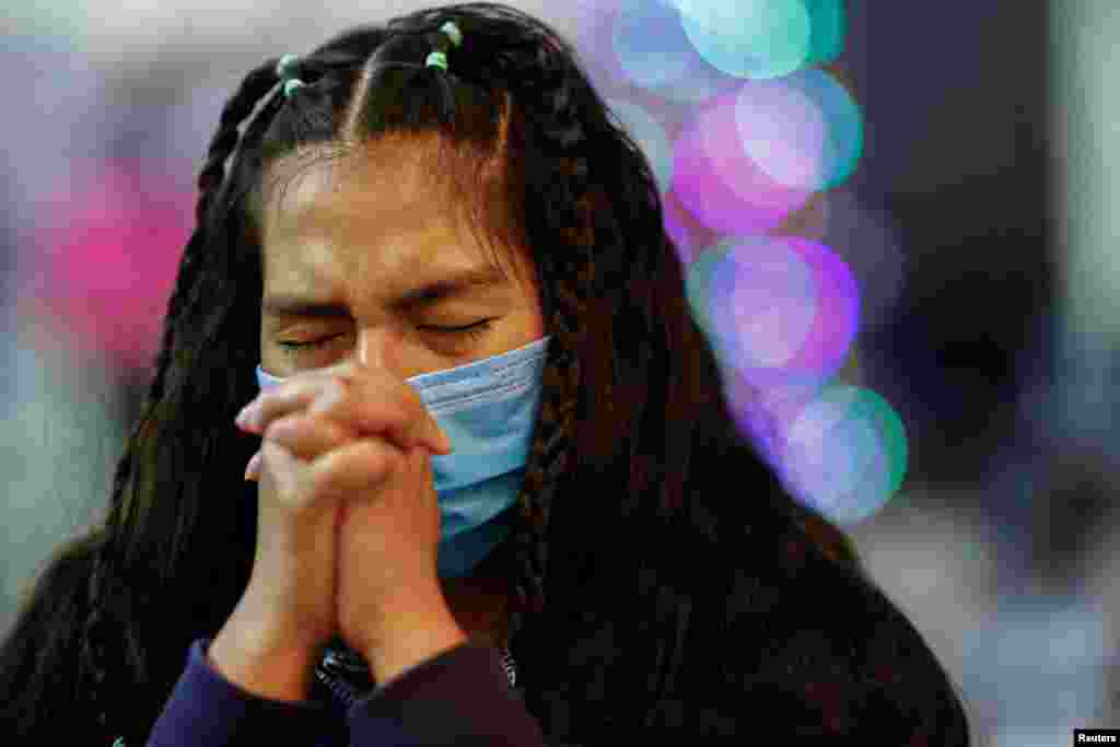 O imigrantă se roagă în noaptea de Revelion pe care o petrece în adăpostul El Buen Samaritano din Ciudad Juarez, Mexic.
