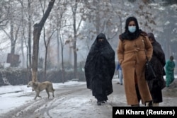 Афганские женщины идут по улице во время снегопада в Кабуле, Афганистан, 3 января 2022 года