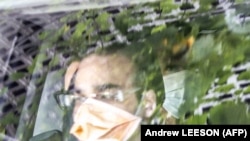 Automobil koji napušta imigracioni centar u Melburnu, veruje se da je osoba pozadi desno teniser Srbije Novak Đoković. Snimak je preuzet sa AFPTV. 10. januar 2022.