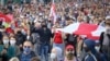 People with old Belarusian national flags march during an opposition rally to protest the official presidential election results in Minsk on October 4.