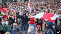 People with old Belarusian national flags march during an opposition rally to protest the official presidential election results in Minsk on October 4.