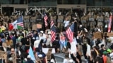 Agenți ai Gărzii Naționale și ai Serviciului Vamal supraveghează manifestanții adunați în fața unei9 clădirii federale înainte de intrarea în vigoare a interdicției de circulație. Los Angeles. 10 iunie 2025.
