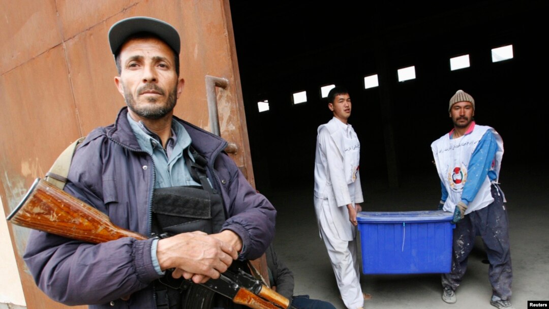 Afghan Election Commission workers carry a ballot box as a police officer stands guard at a warehouse in Herat on April 3.