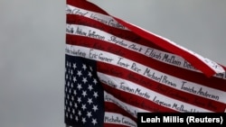 Превртено американско знаме со имиња на Афроамериканци убиени во полициски притвор и други инциденти на протестен марш во Минесота, 13 април 2021 година.