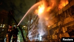 Ukrainian firefighters work at the site of an apartment building damaged by a Russian missile strike late on October 13