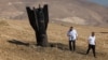 Two Israeli men examine a fallen rocket half-buried in the ground on the outskirts of Jericho on June 8 following attacks by Iranian and Iran-backed Houthi rebel. 